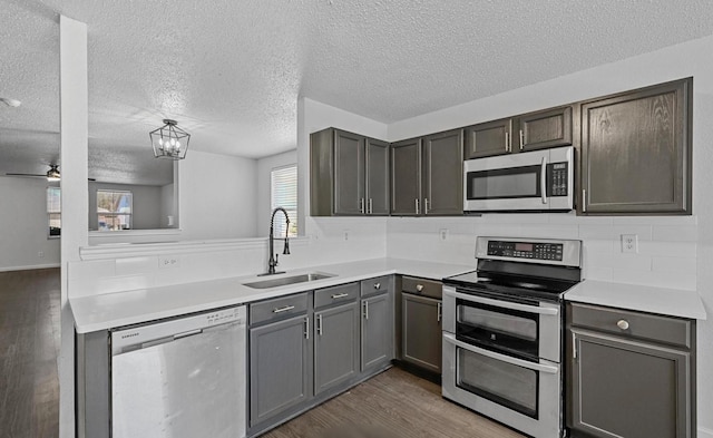 kitchen with a sink, wood finished floors, stainless steel appliances, light countertops, and decorative backsplash