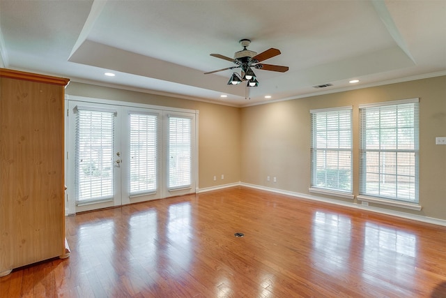 spare room with light wood-type flooring, a tray ceiling, ceiling fan, and french doors