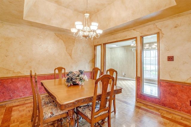 dining area with an inviting chandelier, a tray ceiling, and parquet flooring