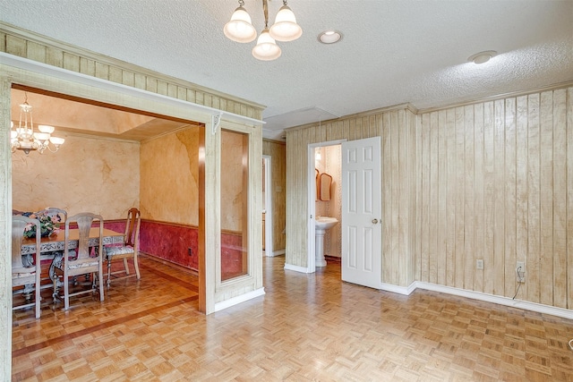 interior space with a textured ceiling, wood walls, parquet flooring, and a notable chandelier