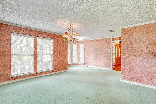 carpeted empty room with a textured ceiling, crown molding, and an inviting chandelier