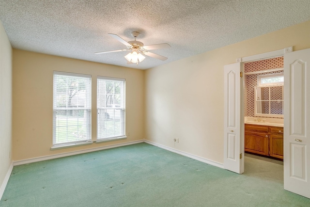 spare room featuring ceiling fan, light colored carpet, and a textured ceiling