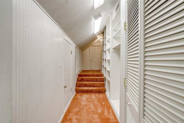 walk in closet with light colored carpet and vaulted ceiling