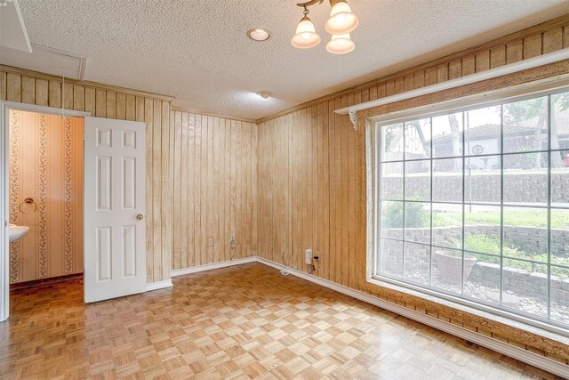 unfurnished room featuring wood walls, parquet flooring, and a textured ceiling