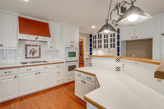 kitchen featuring white appliances, white cabinetry, light hardwood / wood-style flooring, and decorative light fixtures