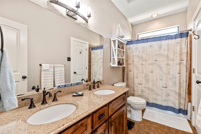 bathroom with tile patterned flooring, toilet, and double sink vanity