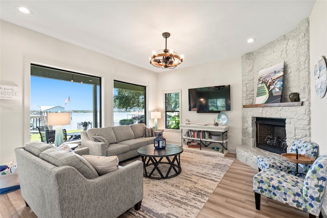 living room featuring a fireplace, a chandelier, and light wood-type flooring