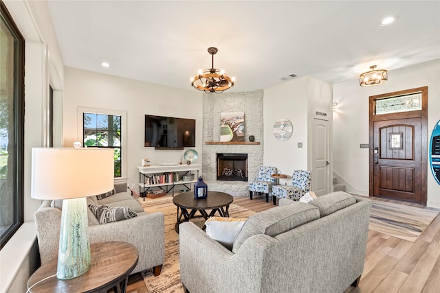 living room featuring a fireplace, light hardwood / wood-style flooring, and an inviting chandelier