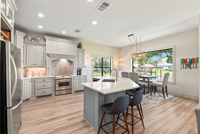 kitchen featuring light wood-type flooring, backsplash, gray cabinetry, appliances with stainless steel finishes, and sink