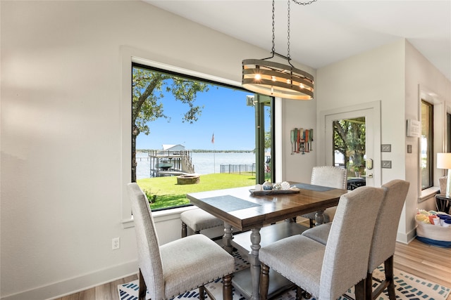 dining room featuring wood-type flooring, a notable chandelier, and a water view