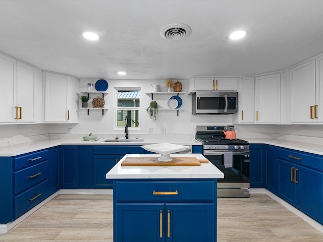 kitchen with white cabinets, appliances with stainless steel finishes, blue cabinets, and sink