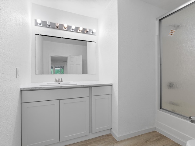 bathroom with vanity, hardwood / wood-style flooring, and enclosed tub / shower combo