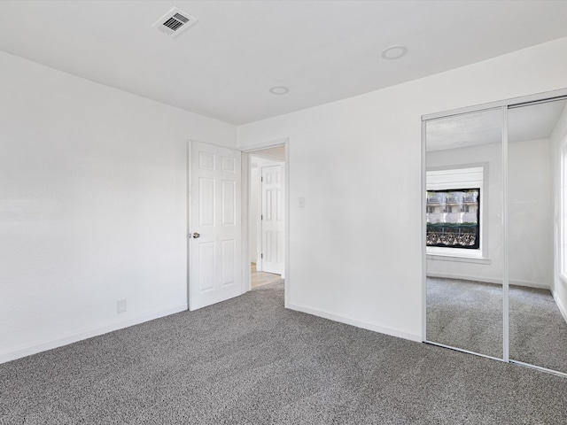 unfurnished bedroom with dark colored carpet and a closet