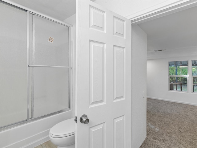 bathroom with combined bath / shower with glass door and toilet