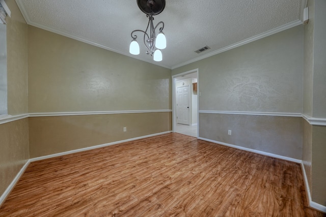 unfurnished room with a notable chandelier, a textured ceiling, light hardwood / wood-style flooring, and crown molding