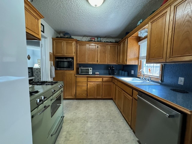 kitchen featuring decorative backsplash, appliances with stainless steel finishes, light tile patterned floors, sink, and a textured ceiling