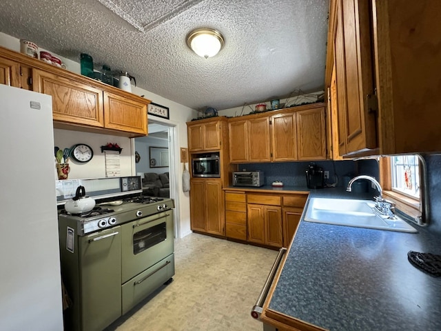 kitchen with sink, range with two ovens, white fridge, and a textured ceiling