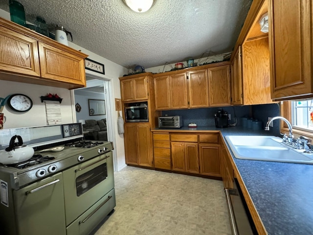 kitchen with dishwasher, sink, range with two ovens, a textured ceiling, and light tile patterned floors