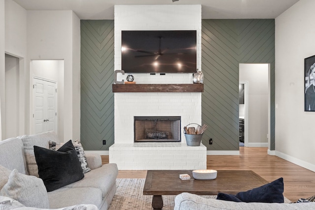 living room with a fireplace, light hardwood / wood-style floors, and brick wall