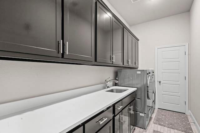 clothes washing area with light tile patterned flooring, sink, independent washer and dryer, and cabinets