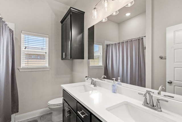 bathroom with tile patterned flooring, toilet, double vanity, and a healthy amount of sunlight