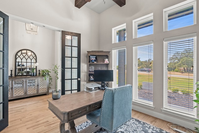 home office with a towering ceiling, beam ceiling, light wood-type flooring, and ceiling fan