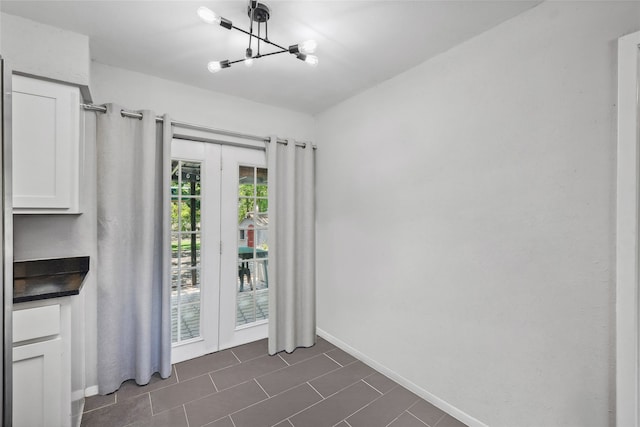 kitchen featuring white cabinetry, stainless steel refrigerator, dark wood-type flooring, and a notable chandelier