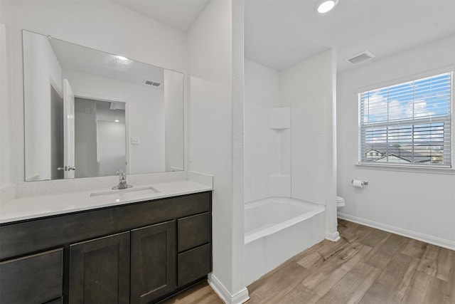 full bathroom featuring toilet, hardwood / wood-style floors, vanity, and washtub / shower combination