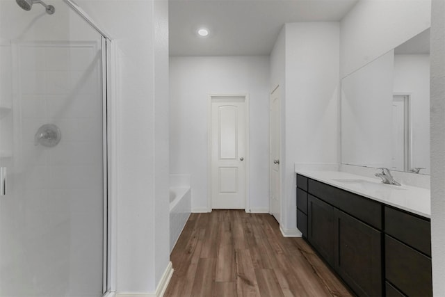 bathroom featuring a bathtub, baseboards, wood finished floors, a shower stall, and vanity
