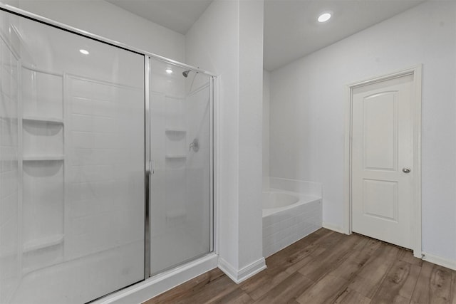 bathroom featuring recessed lighting, wood finished floors, a garden tub, and a stall shower