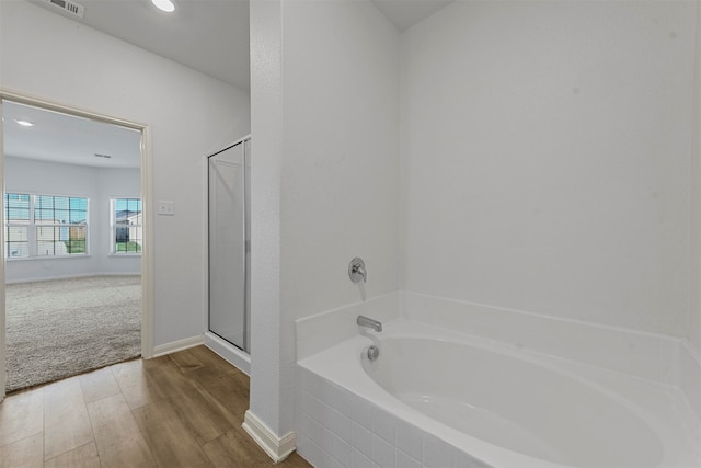 bathroom with independent shower and bath and hardwood / wood-style floors