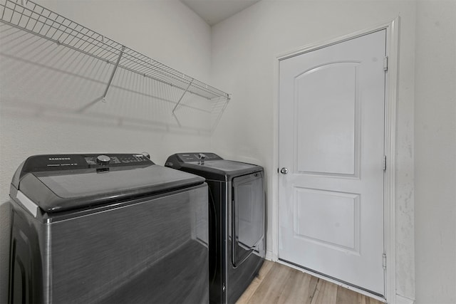 clothes washing area featuring washer and clothes dryer and light wood-type flooring