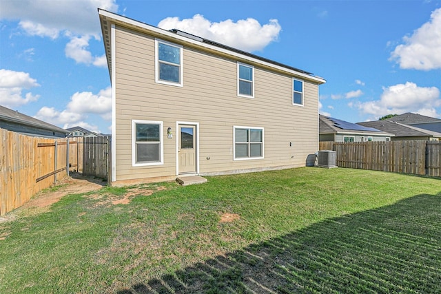 rear view of house with a yard, central AC, and a fenced backyard