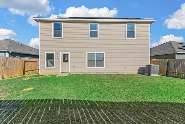 rear view of house with a fenced backyard, a yard, and cooling unit