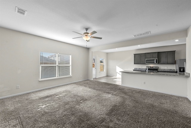 unfurnished living room featuring light colored carpet, a textured ceiling, sink, and ceiling fan