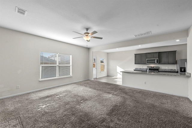unfurnished living room with ceiling fan, carpet floors, visible vents, and baseboards