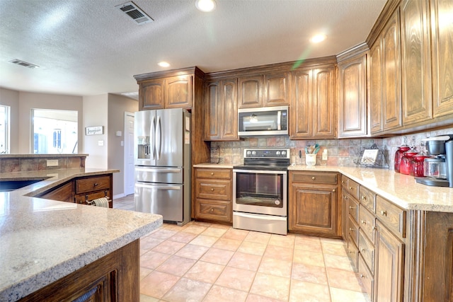 kitchen featuring decorative backsplash, stainless steel appliances, sink, light tile patterned floors, and a textured ceiling