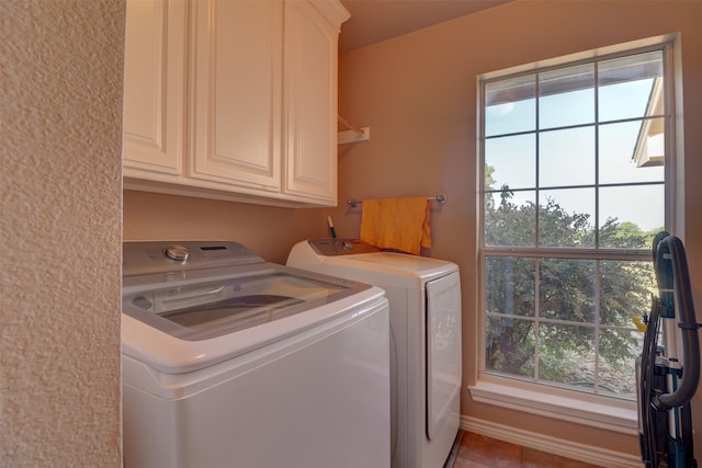 washroom featuring tile patterned flooring, plenty of natural light, washing machine and dryer, and cabinets