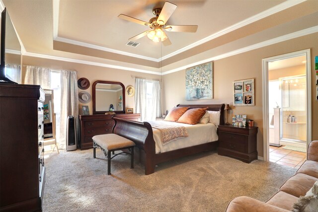 carpeted bedroom featuring ceiling fan, a raised ceiling, connected bathroom, and multiple windows