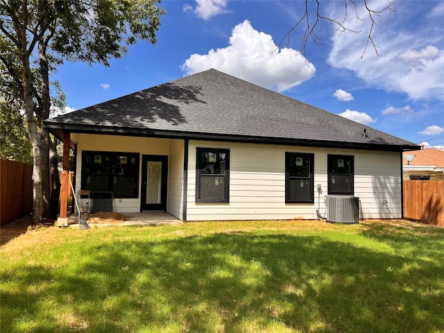 rear view of house with cooling unit and a lawn