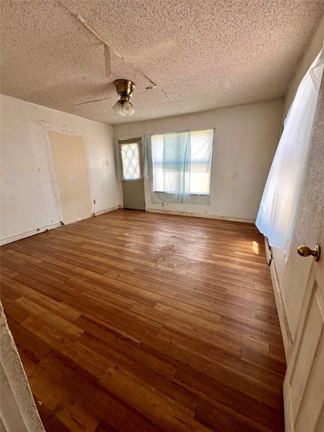 empty room with ceiling fan, wood-type flooring, and a textured ceiling