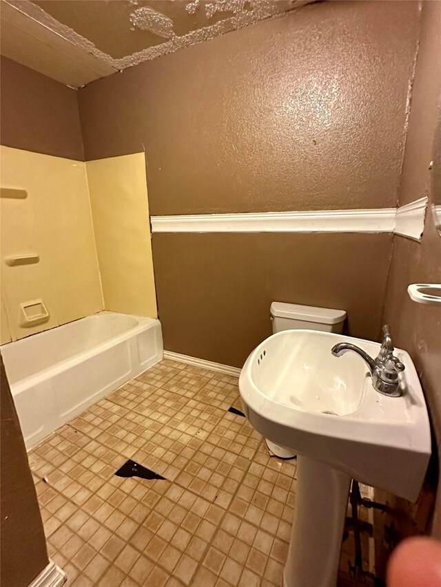 bathroom featuring tile patterned floors, toilet, and a bathtub