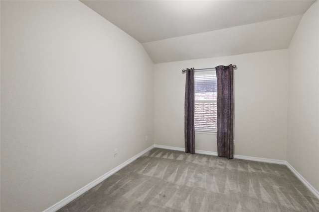 carpeted spare room featuring vaulted ceiling