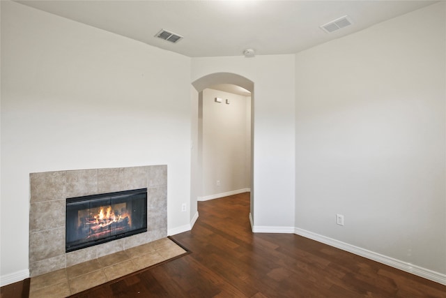 unfurnished living room featuring wood-type flooring and a tile fireplace