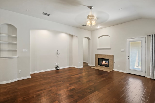 unfurnished living room featuring lofted ceiling, dark wood-type flooring, a tile fireplace, and ceiling fan