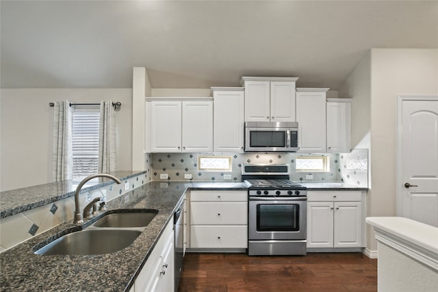 kitchen with appliances with stainless steel finishes, white cabinetry, dark stone counters, and dark hardwood / wood-style flooring