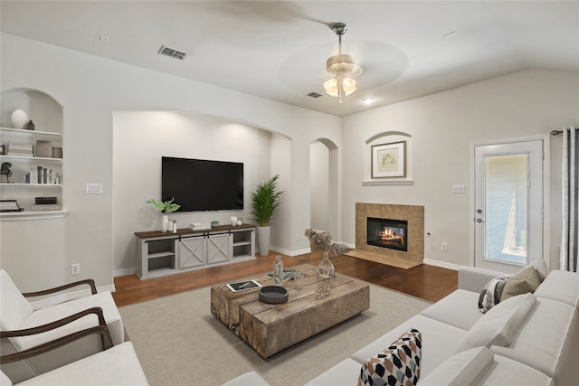 living room featuring hardwood / wood-style flooring, a tile fireplace, vaulted ceiling, and ceiling fan