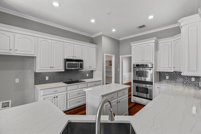 kitchen featuring dark hardwood / wood-style floors, tasteful backsplash, stainless steel appliances, white cabinetry, and light stone counters