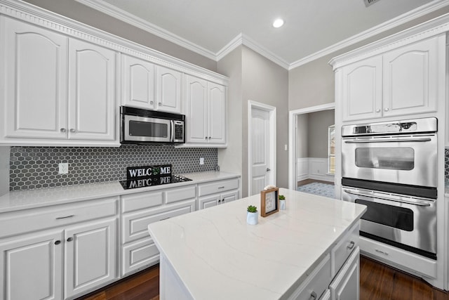 kitchen featuring tasteful backsplash, appliances with stainless steel finishes, ornamental molding, dark wood-type flooring, and white cabinetry