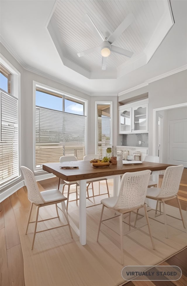 dining space featuring crown molding, a raised ceiling, ceiling fan, and light hardwood / wood-style floors